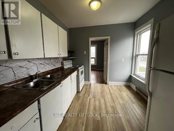 Peterborough (Town Ward 3) multi-family for rent - A kitchen with white cabinets and a wooden floor.