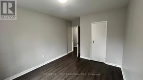 London East (East B) house for rent - A brokerage sign is on the wall of a white room with wood flooring and a door.