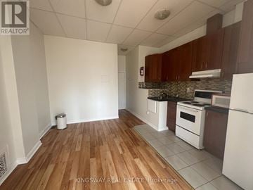Toronto (Roncesvalles) townhouse for rent - A kitchen with white appliances and wooden floors.