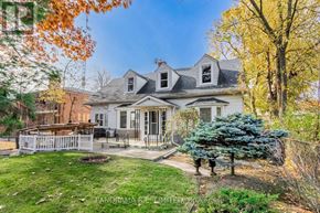 Toronto (Long Branch) apartment for rent - A house with a white picket fence and a tree with blue leaves.