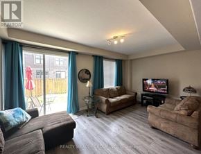 Hamilton (Stoney Creek) townhouse for rent - A living room with a flat screen TV and a balcony with a red umbrella.