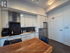 Toronto (Banbury-Don Mills) condo for rent - A kitchen with a wooden table and chairs in the foreground.