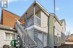 Ottawa condo for rent - A house with a grey and white exterior and a metal staircase leading to the second floor.