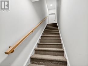 St. Catharines (E. Chester) townhouse for rent - A staircase with a wooden handrail and beige carpeted steps.