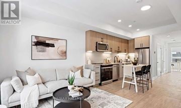 Toronto (Newtonbrook West) townhouse for rent - A modern living room with a white sofa and a kitchen area in the background.