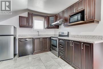 Oshawa (Central) triplex for rent - A kitchen with brown cabinets and a white refrigerator.