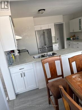 New Tecumseth apartment for rent - A kitchen with a sink, refrigerator, and cabinets.
