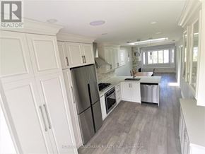 Toronto (Briar Hill-Belgravia) apartment for rent - A kitchen with white cabinets and a black fridge.