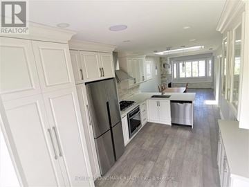 Toronto (Briar Hill-Belgravia) apartment for rent - A kitchen with white cabinets and a black fridge.