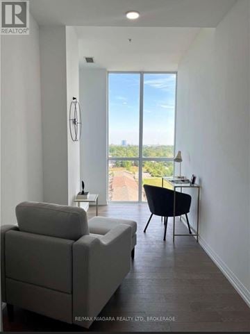 Niagara Falls (Oldfield) condo for rent - A living room with a grey couch and a black chair with a view of the city.