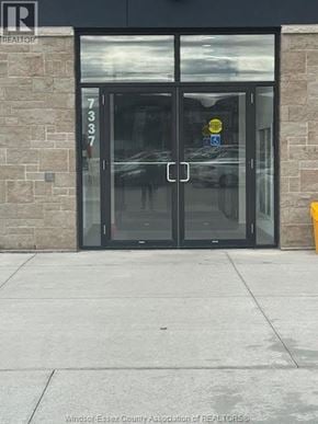 Lasalle condo for rent - The entrance to a building with glass doors and a stone wall.
