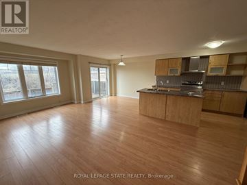 Hamilton (Stoney Creek Mountain) townhouse for rent - A spacious room with wooden flooring and a kitchen area with cabinets and a stove.