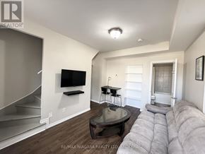 Niagara Falls (Downtown) duplex for rent - A living room with a grey couch and a television on the wall.