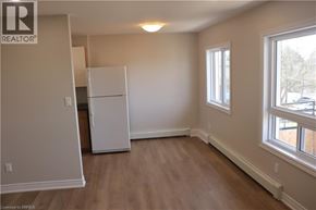 Brantford apartment for rent - A white refrigerator in a room with wooden floors and a window.