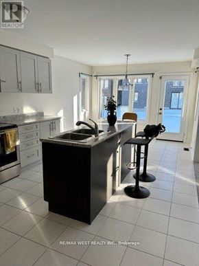 New Tecumseth (Alliston) apartment for rent - A kitchen with a black island and white cabinets.