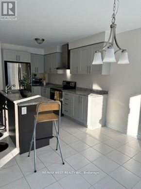 New Tecumseth (Alliston) apartment for rent - A kitchen with a white tile floor and a hanging light fixture.