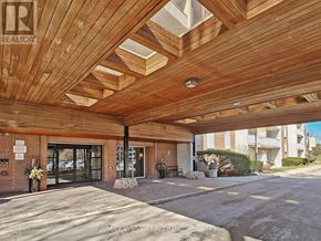 Mississauga (Applewood) condo for rent - A wooden covered walkway leads to a building with a sign that says RE/MAX West Realty.