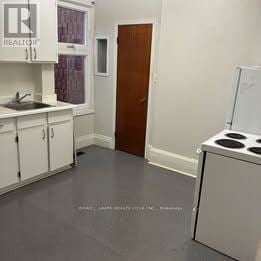 Toronto (Trinity-Bellwoods) apartment for rent - A kitchen with white cabinets and a wooden door.