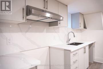 Toronto (Islington-City Centre West) duplex for rent - A white kitchen with a sink and a stainless steel range hood.