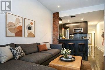 Toronto (South Riverdale) duplex for rent - A living room with a grey couch and a coffee table with flowers on it.