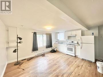 Ottawa multi-family for rent - A kitchen with white appliances and wooden floors.
