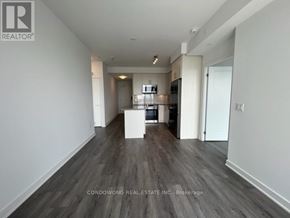 Richmond Hill (Langstaff) condo for rent - A spacious room with a kitchen in the background and a white box in the middle of the room.