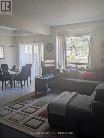 Hamilton (Stoney Creek) townhouse for rent - A living room with a grey couch and a dining table with chairs.