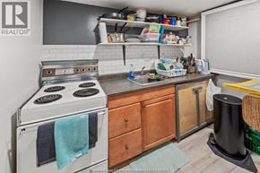 Windsor apartment for rent - A small, cluttered kitchen with a stove, sink, and wooden cabinets.