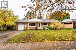 Kitchener apartment for rent - A house with a white garage door is surrounded by trees with yellow leaves.
