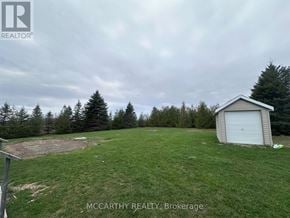 Melancthon apartment for rent - A grassy field with a shed and trees in the background.