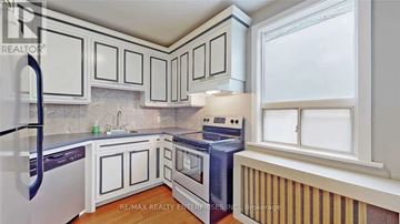 Mississauga (Port Credit) apartment for rent - A kitchen with white cabinets and a black refrigerator.