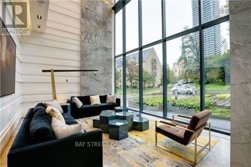 Toronto (Bay Street Corridor) condo for rent - A living room with a black couch and a brown chair.