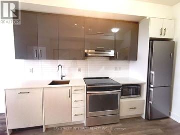Toronto (Don Valley Village) condo for rent - A modern kitchen with a stainless steel refrigerator and white cabinets.
