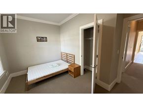 Burnaby apartment for rent - A bedroom with a bed, a bench, and a door.