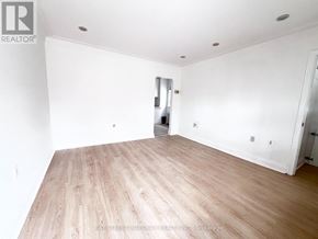 Toronto (Briar Hill-Belgravia) apartment for rent - A spacious room with wooden flooring and white walls.