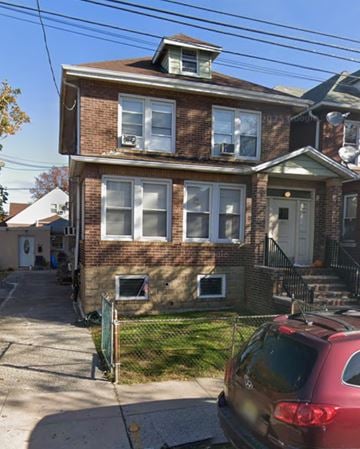 North Bergen apartment for rent - A red car is parked in front of a brick house.
