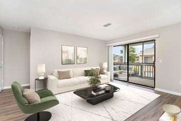 Wilmington apartment for rent - A living room with a green armchair, a white sofa, and a coffee table with a plant on it.