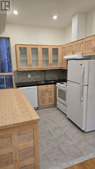 Toronto (Moss Park) triplex for rent - A kitchen with wooden cabinets and a white refrigerator.