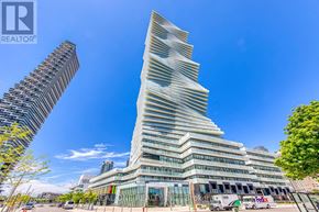 Mississauga (City Centre) condo for rent - A tall, modern building with a unique design stands in the foreground with a clear blue sky above.