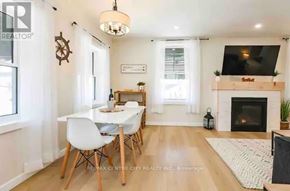 Central Elgin (Port Stanley) condo for rent - A dining room with a white table and chairs, a fireplace, and a television mounted above it.