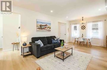 Central Elgin (Port Stanley) condo for rent - A living room with a black sofa, a coffee table, and a painting on the wall.