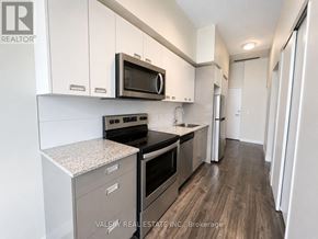 Waterloo condo for rent - A kitchen with white cabinets and a microwave above the stove.