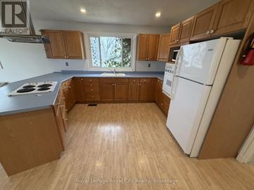 Guelph (Junction/Onward Willow) multi-family for rent - A kitchen with wooden cabinets and a white refrigerator.