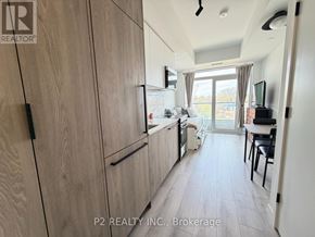 Toronto (Centennial Scarborough) condo for rent - A kitchen with wooden cabinets and a sliding glass door leading to a balcony.