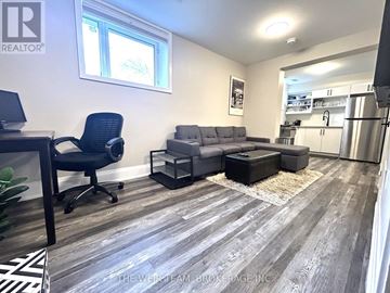 Toronto (East End-Danforth) apartment for rent - A well-lit living room with a grey sofa and a black chair.