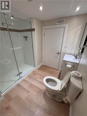 Brantford apartment for rent - A white toilet in a bathroom with a glass shower door.