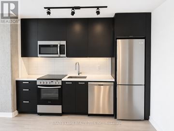 Toronto (Moss Park) condo for rent - A modern kitchen with black cabinets and stainless steel appliances.