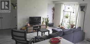 Kitchener triplex for rent - A living room with a grey couch and a television on a wooden stand.