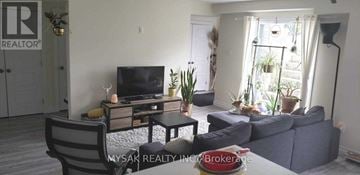 Kitchener triplex for rent - A living room with a grey couch and a television on a wooden stand.