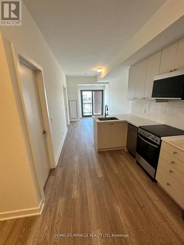Clarington (Bowmanville) condo for rent - A kitchen with white cabinets and a black stove top oven.